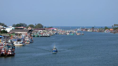 Boats moored in sea against clear blue sky