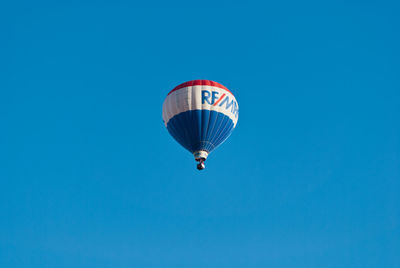 Low angle view of balloons against clear blue sky