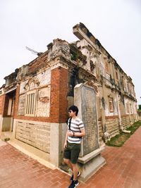 Woman standing by building against sky in city