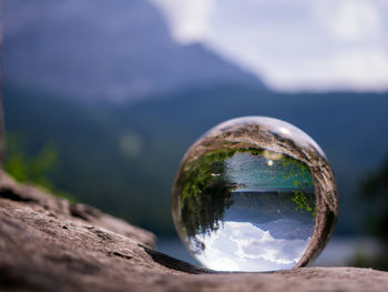 Close-up of crystal ball on rock against eibsee and zugspitze