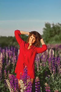 Woman standing by purple flowers on field