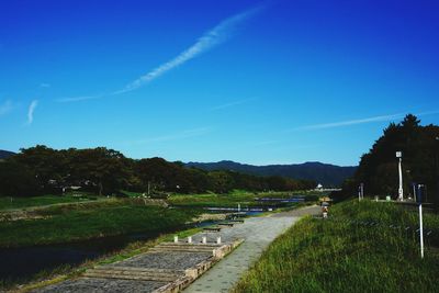 Stream amidst field against blue sky
