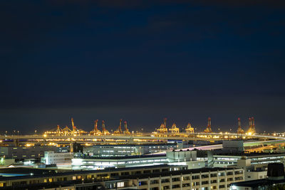 Illuminated factory against sky at night