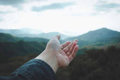 Cropped hand of woman against mountain range