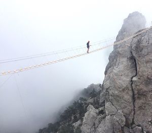 Woman on rope bridge during foggy weather