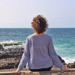 Rear view of woman looking at sea against sky