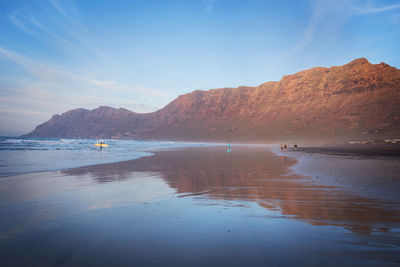 Scenic view of sea and mountains against sky