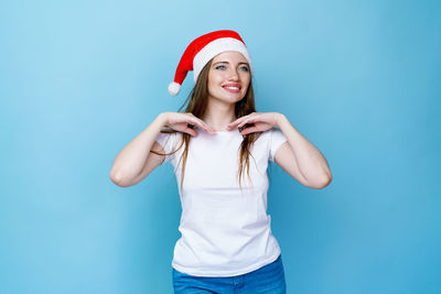 Happy young woman standing against blue background