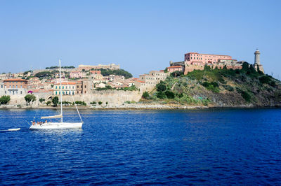 View of buildings by sea against blue sky