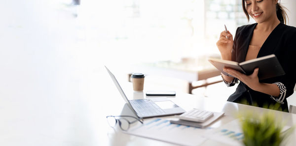 Midsection of businesswoman using laptop on table