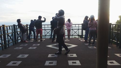 People on railing against sky