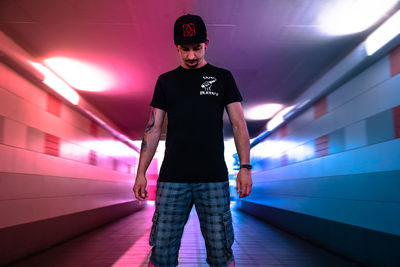 Portrait of young man standing against illuminated wall