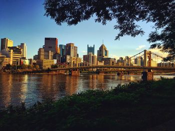 Bridge over river by buildings against sky in city