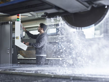 Stonemason operating electric saw through cnc machine at workshop