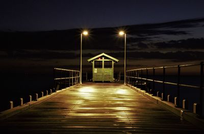 Pier over sea against sky at night