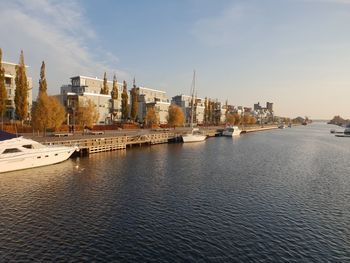 View of buildings by river against sky