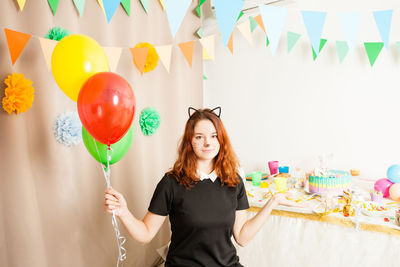 Portrait of smiling woman standing with balloons