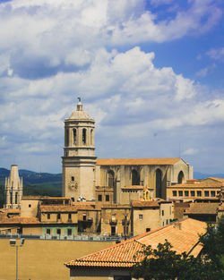 Buildings in city against cloudy sky