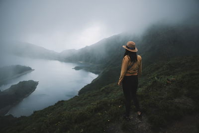 Rear view of woman looking at mountains and lake