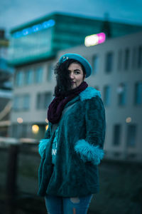 Portrait of young woman standing in city during winter