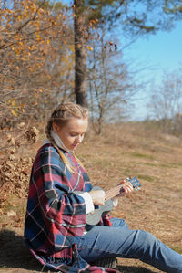 Side view of young woman standing against trees