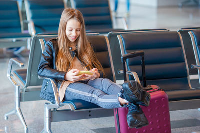 Girl using mobile phone while sitting at airport