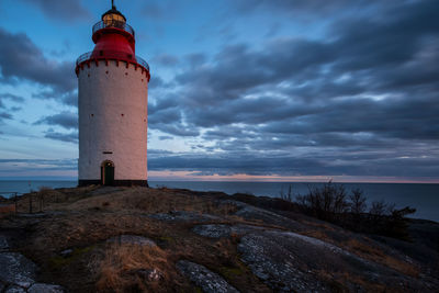 Lighthouse by sea against sky