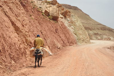 Rear view of man walking on rock formation