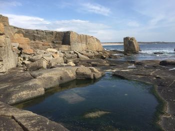 Rock formations by sea against sky