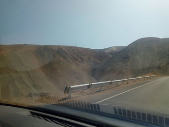 Road leading towards mountain against clear sky