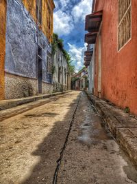 Walkway amidst buildings against sky