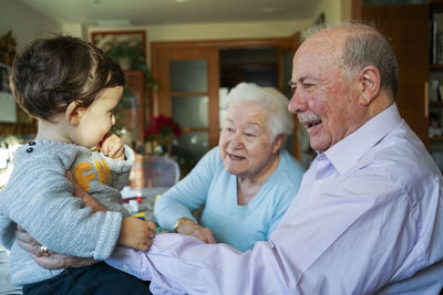 Great-grandparents playing with baby girl at home