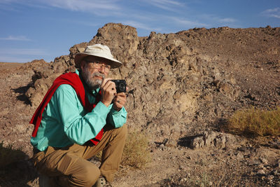 Rear view of man photographing while standing on mountain