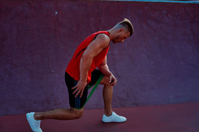 Side view of young man skateboarding against wall