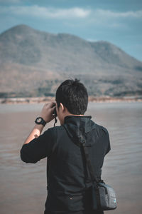 Rear view of man standing against mountain