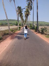 Rear view of woman walking on road against sky