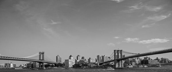 Suspension bridges in city against sky