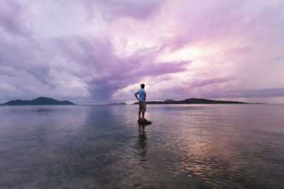 Man standing on sea shore against sky