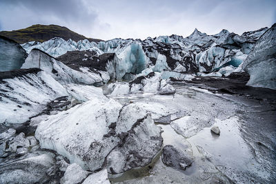 Snow covered rocks against sky