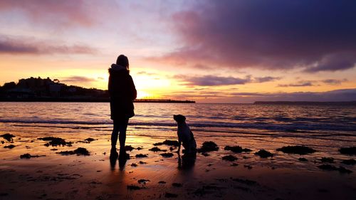 Silhouette man standing on beach against sky during sunset