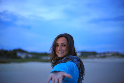 Portrait of smiling woman against blue sky