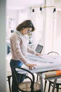 Woman looking at blueprint working at home