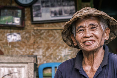 Horizontal portrait of a south asian seior men wearing a traditional balinese cone-shaped hat. 