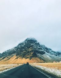 Country road by mountain against sky