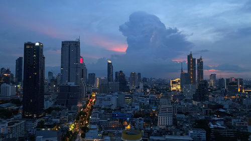 Aerial view of illuminated buildings in city against sky at sunset