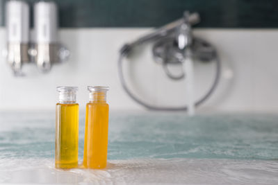 Close-up of yellow shampoo in bottles on bathtub