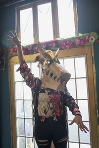 Portrait of young female artist wearing a dragon mask