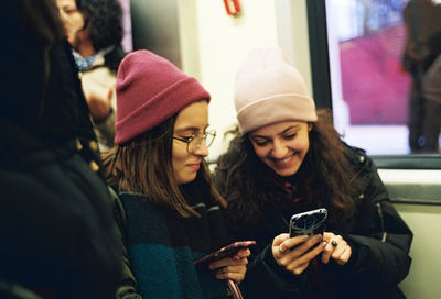 Smiling women using mobile phone while sitting in train