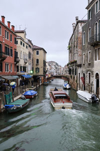 Boats moored on canal amidst buildings in city