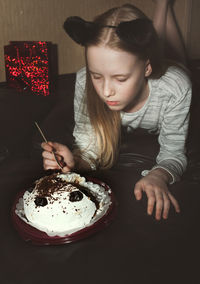Girl holding ice cream on table at home